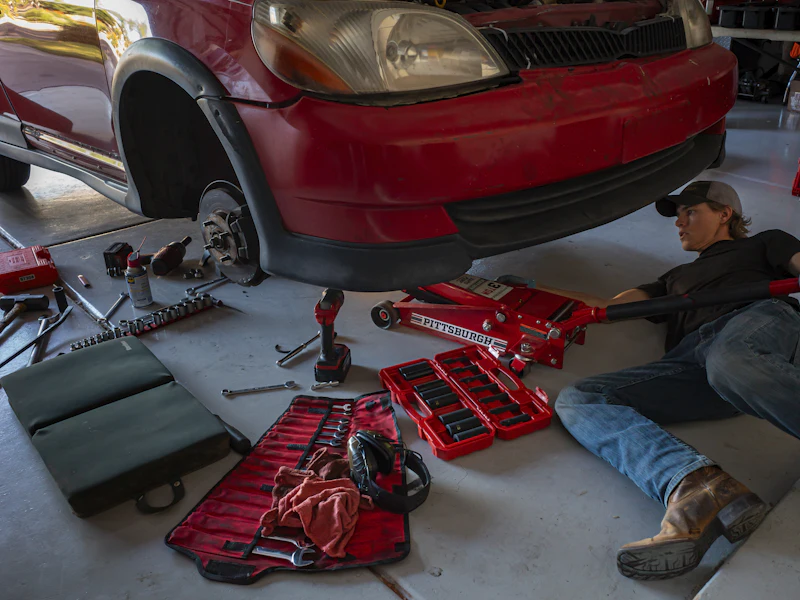 Technician working beneath a car with tools laid out