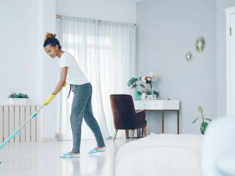 Cleaner mopping the floor of a bright, tidy room