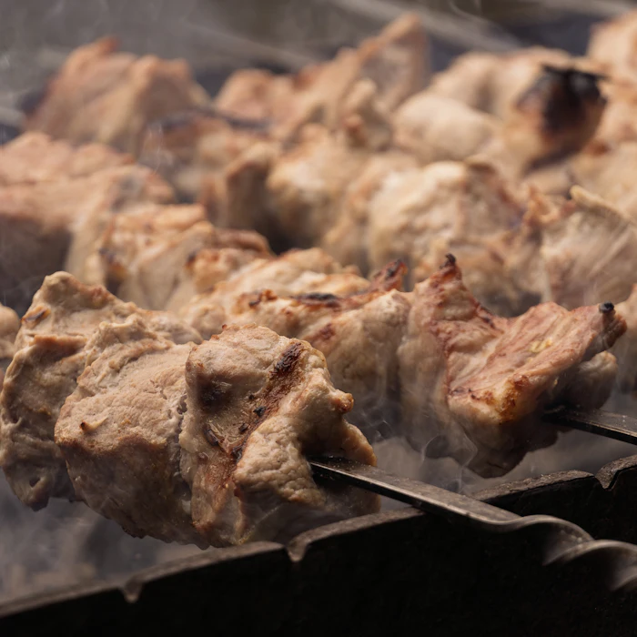 Close-up of lamb pieces searing on the charcoal grill