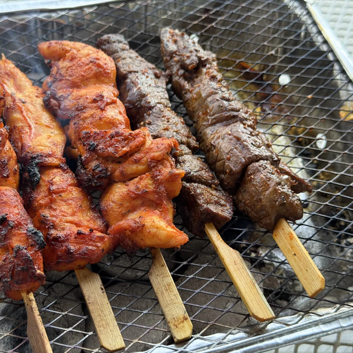 Rows of marinated chicken and lamb skewers on the grill